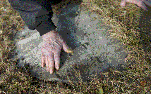 Dick Roberts wipes an old tombstone